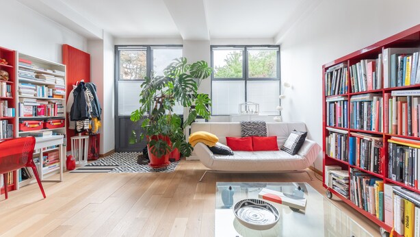 A modern living room with a sofa, red bookshelves, a glass coffee table, and a large plant. - Atelier des Harmonies - L'atelier d'artiste au cœur de Lyon (Lyon)