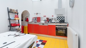 A compact kitchen with red cabinets, a yellow-tiled floor, a built-in oven, and a skylight. - Atelier des Harmonies - L'atelier d'artiste au cœur de Lyon (Lyon)
