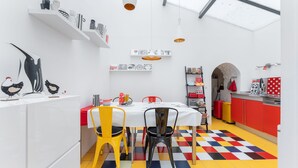 A modern kitchen with a checkered floor, white walls, and red cabinets. - Atelier des Harmonies - L'atelier d'artiste au cœur de Lyon (Lyon)