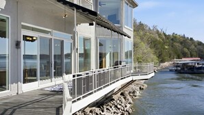 En fastighet vid vattnet med en balkong, stora fönster och utsikt över vattnet.
