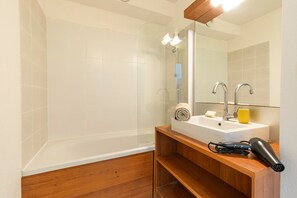 A modern bathroom with a glass-enclosed shower, a wooden vanity with a sink, and a hairdryer on the counter. - Casa Jouarres - Appartement avec terrasse privée (Azille)