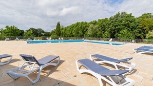 Área da piscina com espreguiçadeiras, piscina e cerca.
