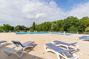 A pool area with lounge chairs, a swimming pool, and a fence. - Casa Jouarres - Appartement avec terrasse privée (Azille)