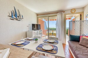 Ein Essbereich mit Tisch für zwei Personen, einem Fernseher und einem Balkon mit Blick.