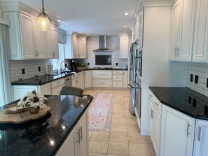 A modern kitchen with white cabinetry, a black countertop, and a central island. - Irish Family Villa! Close to ND! (Granger)