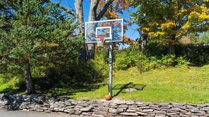 A basketball hoop with a stone wall in the foreground and trees in the background. - Mountainview - Guest House by Avantstay Heated Pool + Hot Tub + Games Lake + Cannoe Near Hunter Mountain (Hensonville)