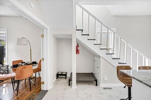A modern interior with a dining area, staircase, and a pet feeding station.