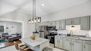 Una cocina moderna con una isla de mármol, electrodomésticos de acero inoxidable y armarios de color gris claro.