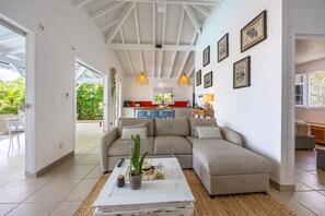 Ein Wohnzimmer mit Ecksofa, Couchtisch und einer Küche im Hintergrund.