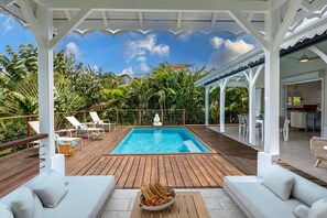Ein Poolbereich mit Liegestühlen, einem Esstisch mit Speisen und Blick auf ein Haus.