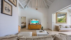 Uma sala de estar ampla com uma televisão grande, um sofá e um armário de madeira.