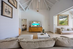 Ein großzügiges Wohnzimmer mit einem großen Fernseher, einer Couch und einem Holzkabinett.