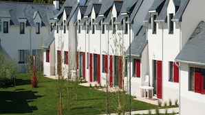 A row of white buildings with red shutters and grey roofs, arranged in a linear fashion. - Cozy Cottage in Queven for 6 (Queven)