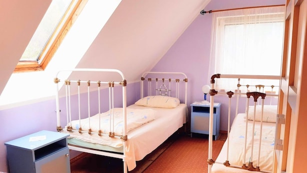 Ein Zimmer mit zwei Einzelbetten, einem kleinen Nachttisch, einem Sessel und einem Fenster mit Blick.