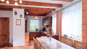 Ein Essbereich mit einem Holztisch und Stühlen, einer Blumenvase und einer Küche im Hintergrund.