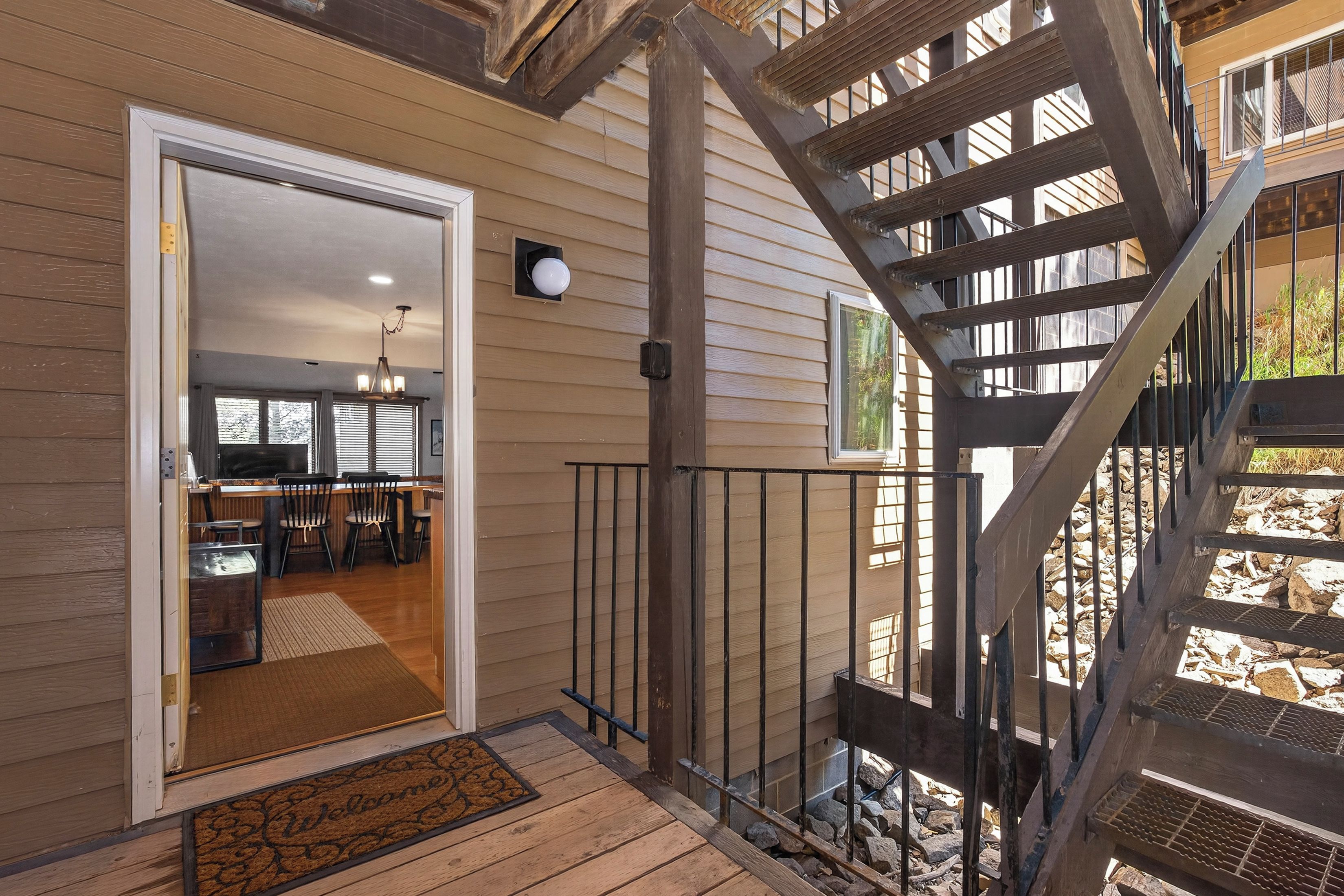 A wooden deck with a metal staircase leading to a second-floor balcony.