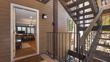 A wooden deck with a metal staircase leading to a second-floor balcony.