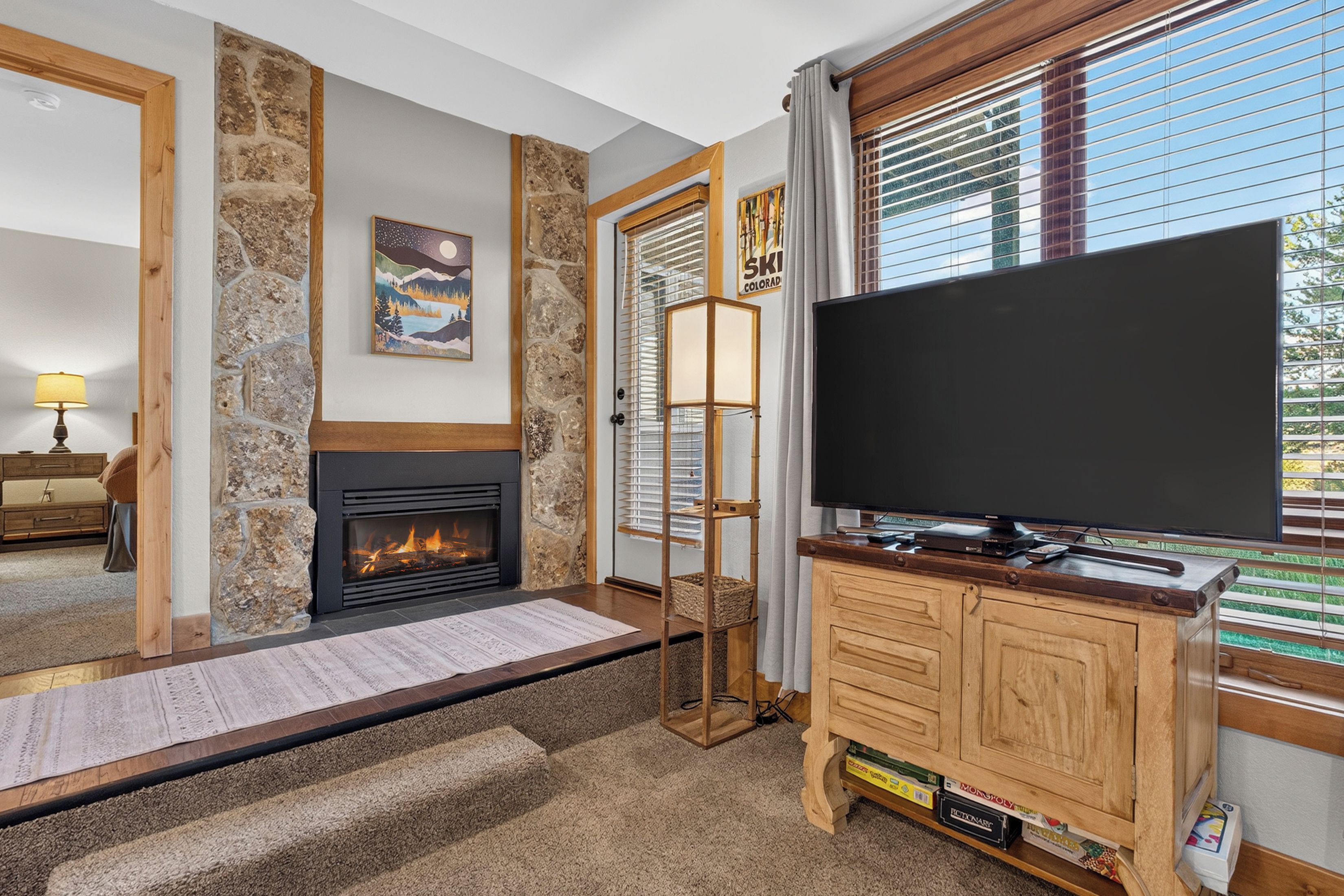 A living room with a fireplace, a television, and a stone wall.