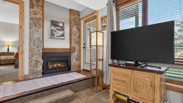 A living room with a fireplace, a television, and a stone wall.