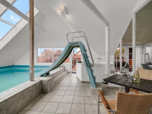 Ein Schwimmbecken mit Rutsche, Tisch mit Stühlen und Ausblick ins Freie.