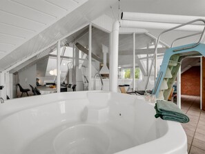 Ein modernes Badezimmer mit einer großen Badewanne, Oberlichtern und einer sichtbaren Treppe, die zu einer oberen Ebene führt.