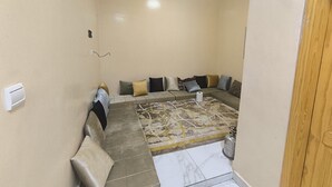 A room with a sectional sofa, a patterned rug, and a gas cylinder.