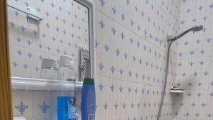 A bathroom with a sink, toilet, and shower. There are toiletries on the sink's edge.