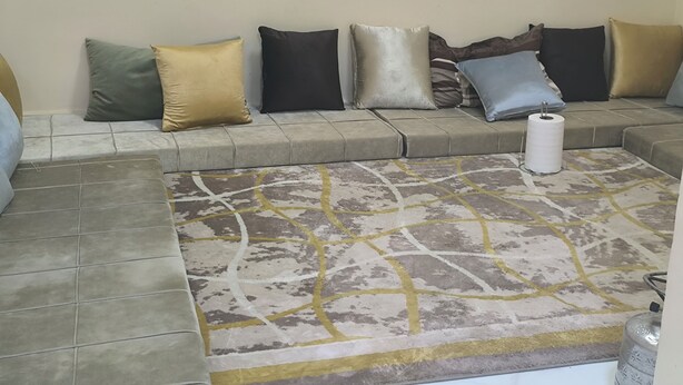 A seating area with a patterned rug, a roll of toilet paper, and a water dispenser.
