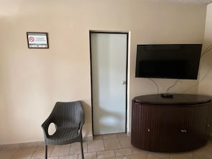 Huoneessa on jalustalla oleva televisio, ovi ja tuoli.
