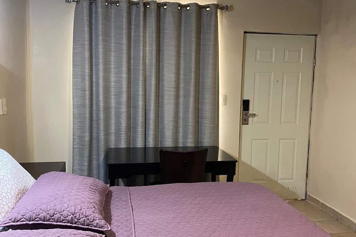 Ein Schlafzimmer mit einem Bett, einem Schreibtisch und einer Tür.