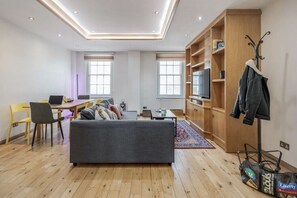 Ein modernes Wohnzimmer mit einer Couch, einem Esstisch und einem Fernseher.