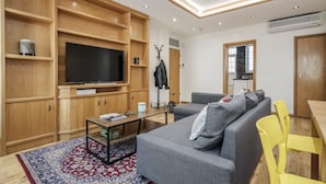 Una sala de estar moderna con televisor, sofá, mesa de centro y estanterías de madera.