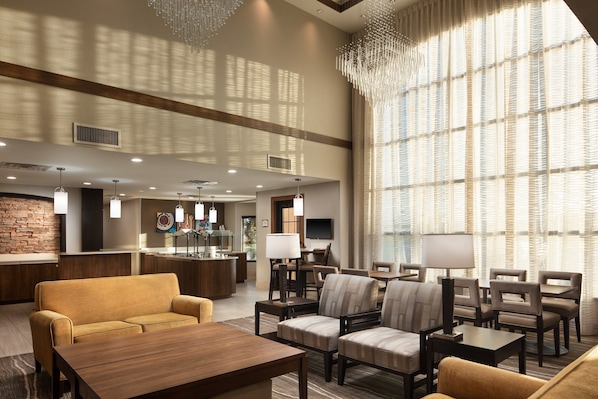 A spacious lobby with a reception desk, seating area, and large windows.
