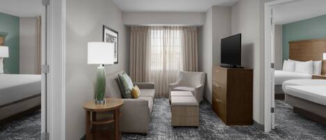 Een hotelkamer met een bed, een televisie, een bank, een bureau en een dressoir.