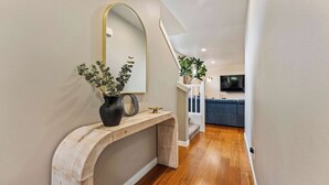 Un couloir avec une console en bois, un miroir et un vase avec des plantes.