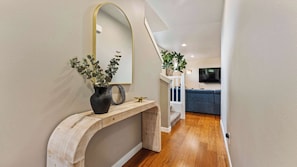 A hallway with a wooden console table, a mirror, and a vase with plants.