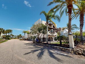 A multi-story building with balconies, palm trees, and a paved road. - Del Mar Home with Rooftop Deck & Ocean Views (St. Augustine)