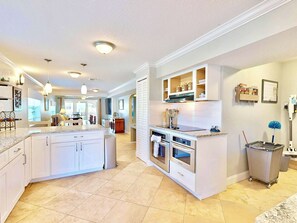 A spacious kitchen with white cabinetry, a central island, and a dining area in the background. - Del Mar Home with Rooftop Deck & Ocean Views (St. Augustine)
