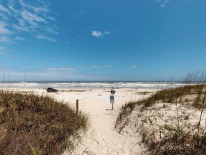 A beach path leading to the ocean with a signpost and a vehicle parked on the sand. - Del Mar Home with Rooftop Deck & Ocean Views (St. Augustine)