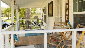 A porch with a wooden chair, a small table, and a hanging light fixture. - Lovely 2-bedroom house with AC in charming Chipley. (Chipley)