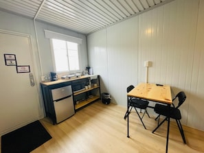 Una cocina compacta equipada con refrigerador, microondas y cafetera. Hay una mesa de comedor con cuatro sillas.