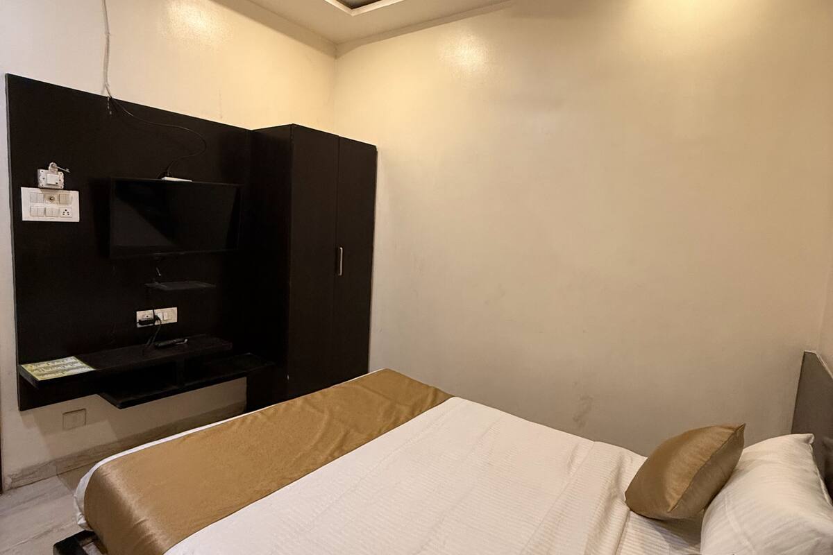 Una habitación de hotel moderna con una cama, un televisor de pantalla plana montado en la pared y un ventilador de techo.