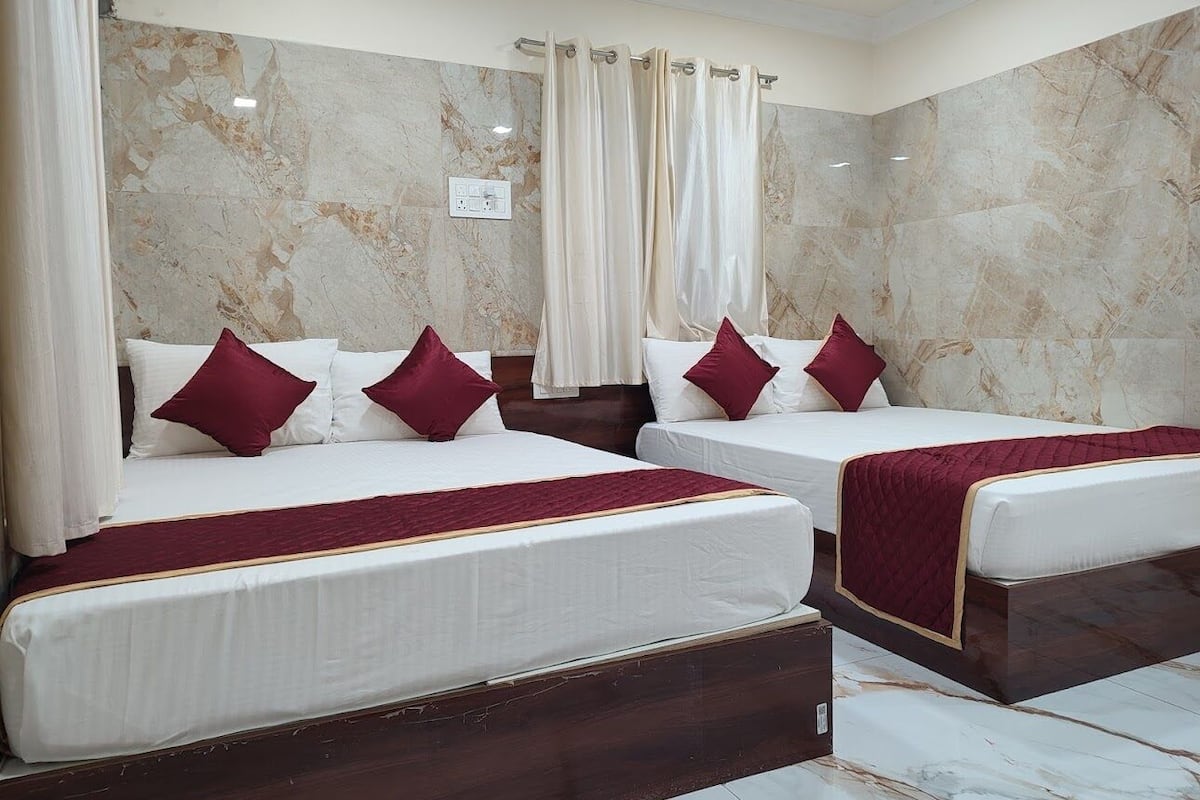 Habitación de hotel con dos camas, paredes de mármol y cortinas.