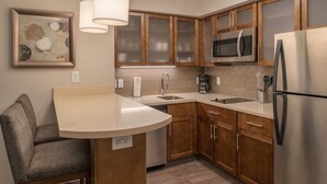 Una cocina con armarios de madera, un refrigerador de acero inoxidable, un microondas y una cafetera.
