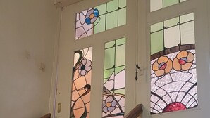 A staircase with white balusters and a wooden handrail leading to a door with stained glass windows. - Vacation apartment for 5 people at Gut Hange by the forest and lake (Freren)