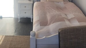 A bedroom with a bed, a nightstand, a lamp, a chair, and a table with a magazine. - Vacation apartment for 5 people at Gut Hange by the forest and lake (Freren)