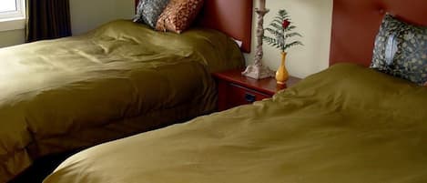 Une chambre d’hôtel avec deux lits, une table de chevet avec une lampe et une fenêtre avec des rideaux.