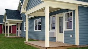 A residential building with a covered porch, a front door, and a small front yard. - Island Sunset Resort (Belle Côte)
