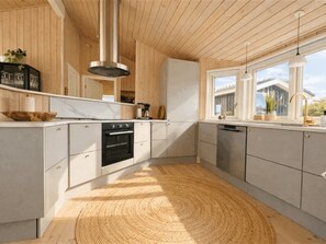 Eine moderne Küche mit Holzschränken, einem eingebauten Backofen und einem großen Fenster.