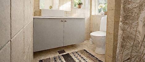 A bathroom with a tiled floor, a sink, a toilet, and a window.